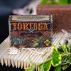 Mydlo-do-brody-Tortuga-110-g-w-ozdobnym-opakowaniu-z-grafika-zolwia-na-brazowym-tle,-widoczne-napisy-“TORTUGA-i-“BEARD-SOAP.-Produkt-lezy-na-falowanej,-jasnej-powierzchni,-w-otoczeniu-roslinnosci-oraz-muszli,-co-nadaje-naturalny-charakter..jpg
